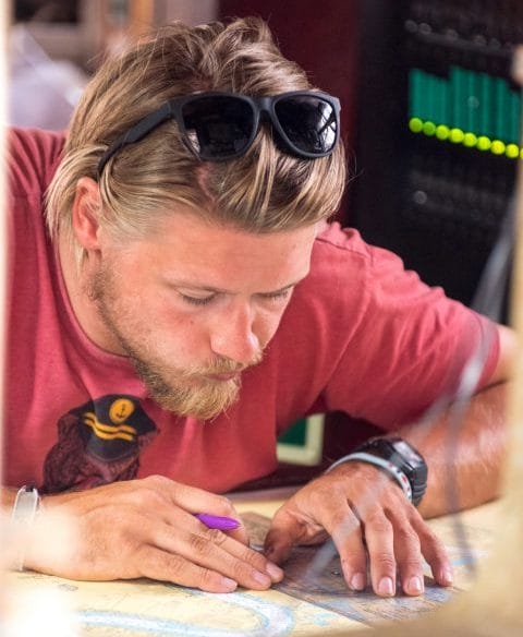 Professional crew officer crew member reading charts noting position sailing Atyla Ship Foundation